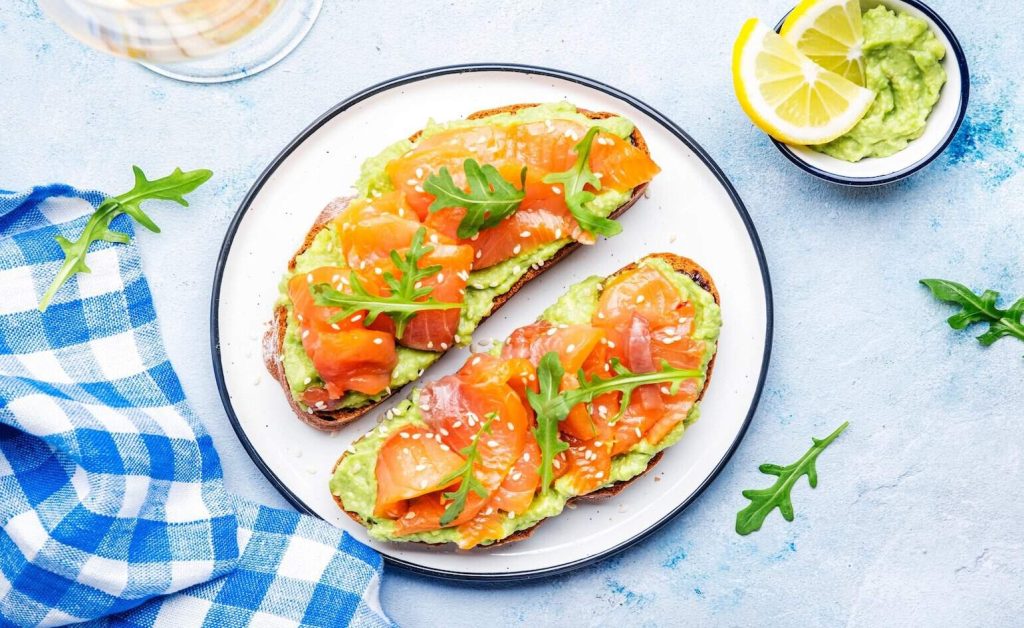 8 Tasty Ways to Get 30g of Protein for Breakfast A plate of 2 avocado toasts with salmon as a tasty breakfast meal with 30g of protein